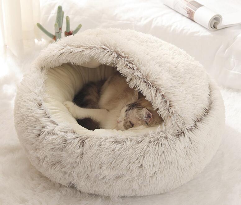 Chat endormi dans un lit à capuche moelleux en fausse fourrure grise, intérieur beige chaud.